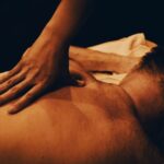 Een masseur die met de hand een ontspannende rugmassage geeft aan een persoon in een warme, rustgevende sfeer.